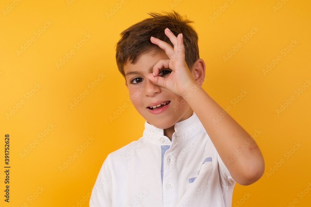 MODELO with happy face smiling doing ok sign with hand on eye looking through finger. MODELO with happy face smiling doing ok sign with hand on eye looking through finger.