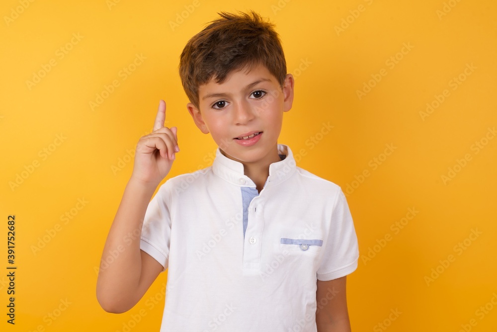 Cute Caucasian little boy standing against yellow background showing and pointing up with fingers number one while smiling confident and happy. Cute Caucasian little boy standing against yellow background showing and pointing up with fingers number one while smiling confident and happy.
