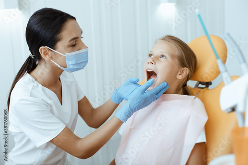 Little girl open mouth for treatment  young female doctor in white coat