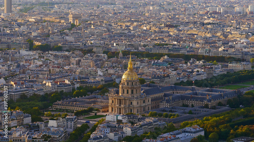 Majestic aerial panoramic view of the dense historic center of Paris, France, with Les Invalides complex (Hôtel national des Invalides) and monument Arc de Triomphe in the beautiful evening sunlight.