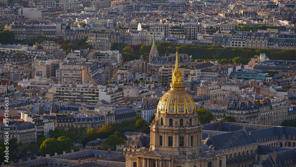 Closeup aerial view of the top of famous Les Invalides dome with the majestic golden colored cupola located in the dense historic center of Paris, France in the beautiful evening sun.