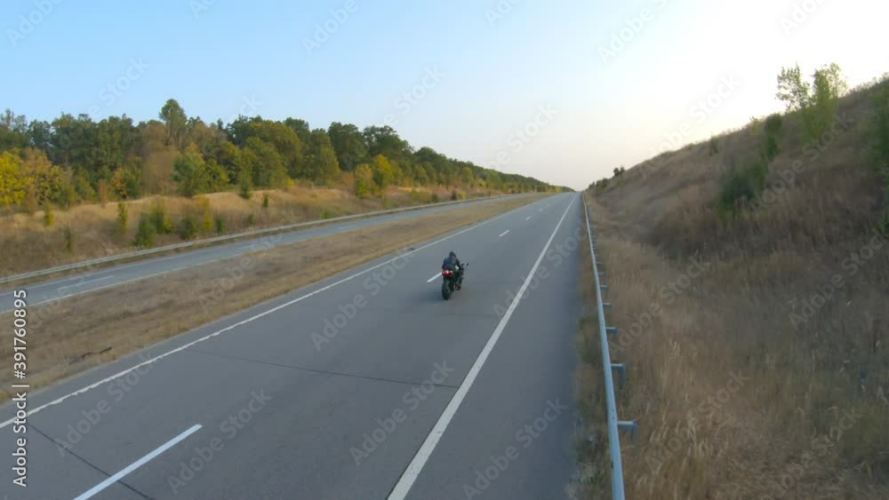 Aerial shot of motorcyclist riding on modern sport motorbike at autumn highway. Biker racing his motorcycle on country road. Guy driving bike during trip. Concept of freedom and adventure at journey Aerial shot of motorcyclist riding on modern sport motorbike at autumn highway. Biker racing his motorcycle on country road. Guy driving bike during trip. Concept of freedom and adventure at journey
