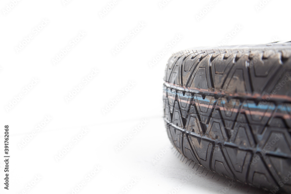 Close-up of the tread of a spare tire of a car on a white background in a photo studio with summer tires. Spare tire for replacement during seasonal car repair in a workshop or garage. Close-up of the tread of a spare tire of a car on a white background in a photo studio with summer tires. Spare tire for replacement during seasonal car repair in a workshop or garage.