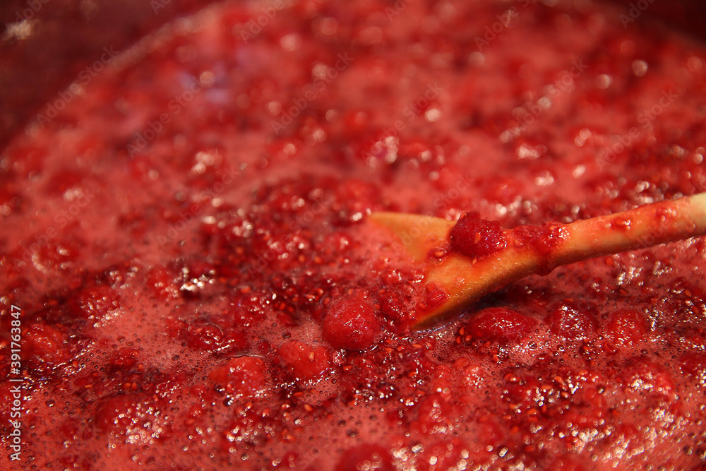 Cooking raspberry jam in a saucepan. Wooden spoon in a saucepan. Cooking raspberry jam in a saucepan. Wooden spoon in a saucepan.