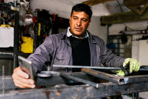 Blacksmith Using Phone in Workshop