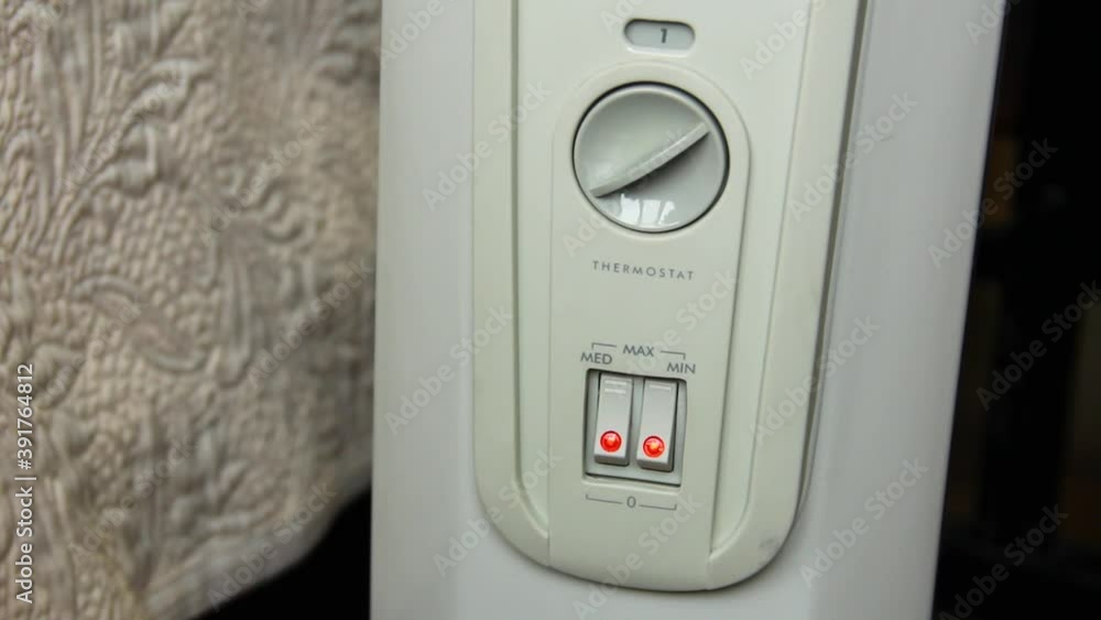 The hand turns on the convector. Electric battery close up The hand turns on the convector. Electric battery close up