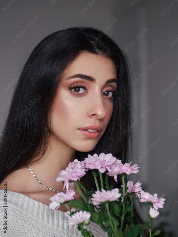 Magnificent portrait of a beautiful brunette young woman with perfect skin makeup closeup flowers bouquet