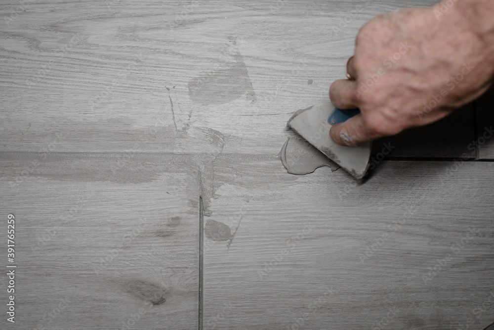 jointing of floor tiles. Grouting tiles seams with a rubber trowel