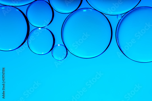 Blue oil drops in water. Bubbles of different sizes on blue abstract background