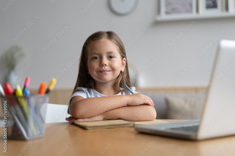Portrait of happy small pupil learning at home. Smiling little child girl enjoying doing lessons in living room. Smart kid schoolgirl looking at camera, studying remotely online. Portrait of happy small pupil learning at home. Smiling little child girl enjoying doing lessons in living room. Smart kid schoolgirl looking at camera, studying remotely online.