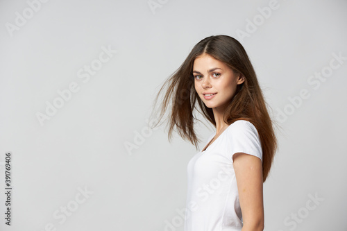 Beautiful woman in a white T-shirt with loose hair side view smile