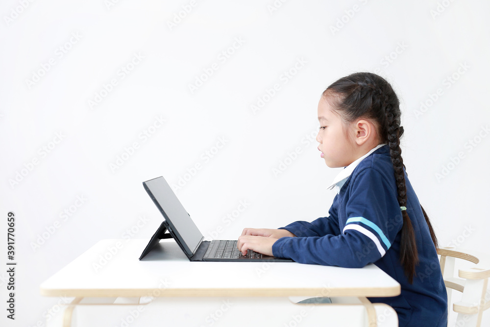 Portrait asian little child girl in school uniform using laptop on table isolated on white background, Studio shot Portrait asian little child girl in school uniform using laptop on table isolated on white background, Studio shot