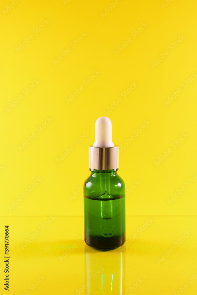 Green bottle on a yellow background with reflection Green bottle on a yellow background with reflection