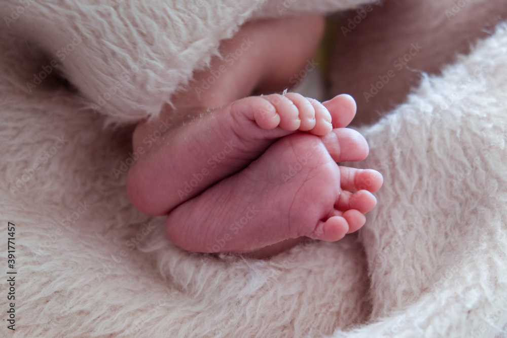 Close-up of unrecognizable cute baby shaking feet while lying in bed. Close-up of unrecognizable cute baby shaking feet while lying in bed.