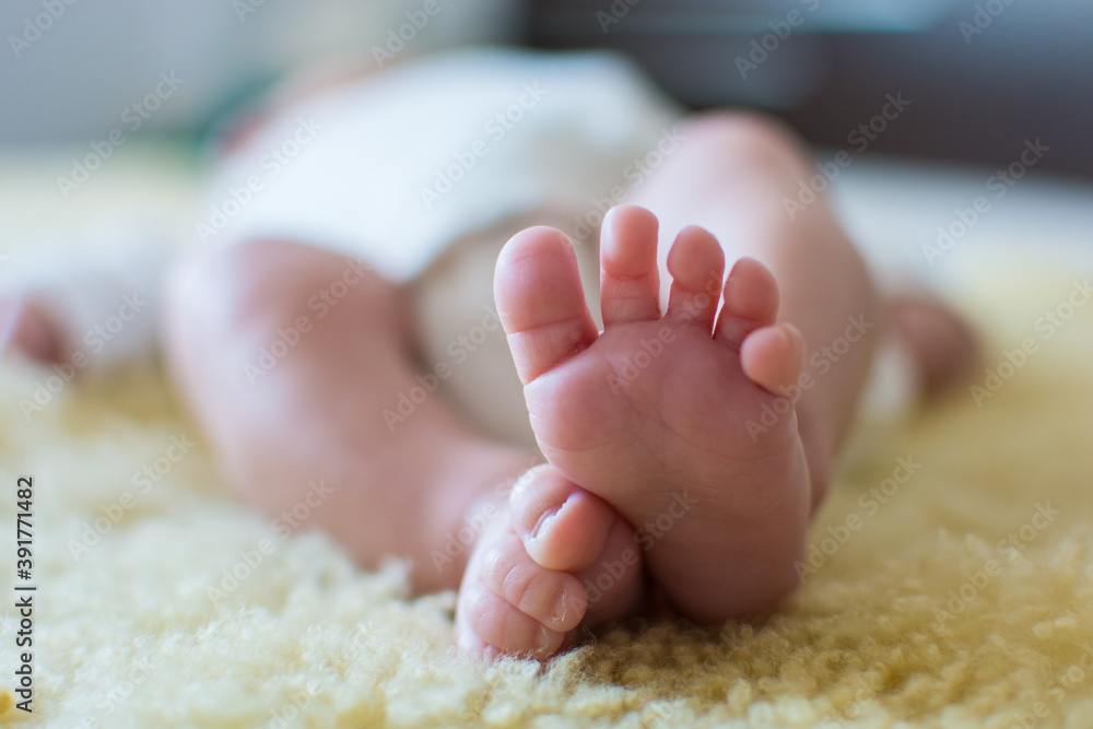 Close-up of unrecognizable cute baby shaking feet while lying in bed. Close-up of unrecognizable cute baby shaking feet while lying in bed.