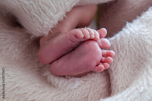 Close-up of unrecognizable cute baby shaking feet while lying in bed.