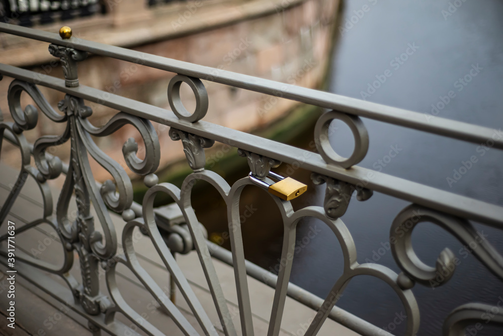  City life backgrounds. A gray hedge by the river. The golden lock is hung on the railing of the bridge. Traditions. Make a wish.