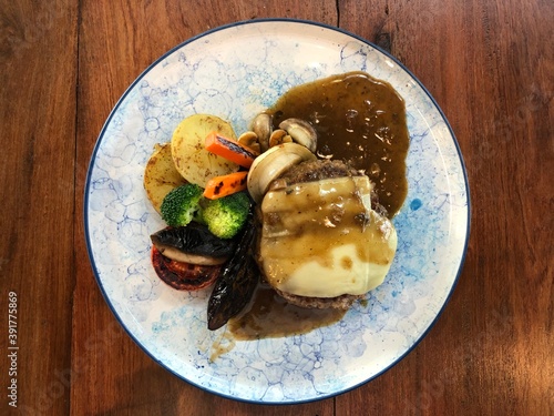 Beef hamburg steak with pepper sauce with cheese and vegetable.