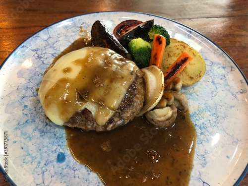 Beef hamburg steak with pepper sauce with cheese and vegetable.