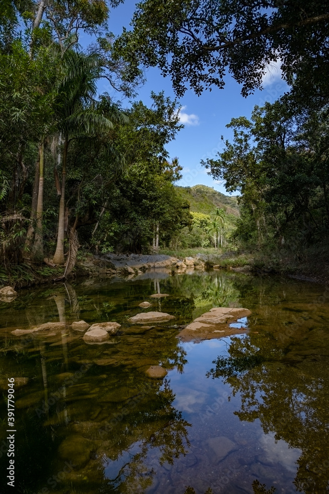 A beautiful mountain stream in the Cuban tropics. Clear water flows from the mountains forming small puddles and lakes. Perfect reflection.