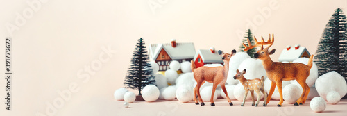 Deer family on Christmas Eve on the background of rural houses, Christmas mockup. Merry Christmas and New Years concept. Banner © Irina