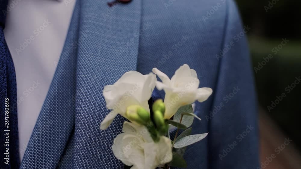 groom's boutonniere of flowers on a blue jacket