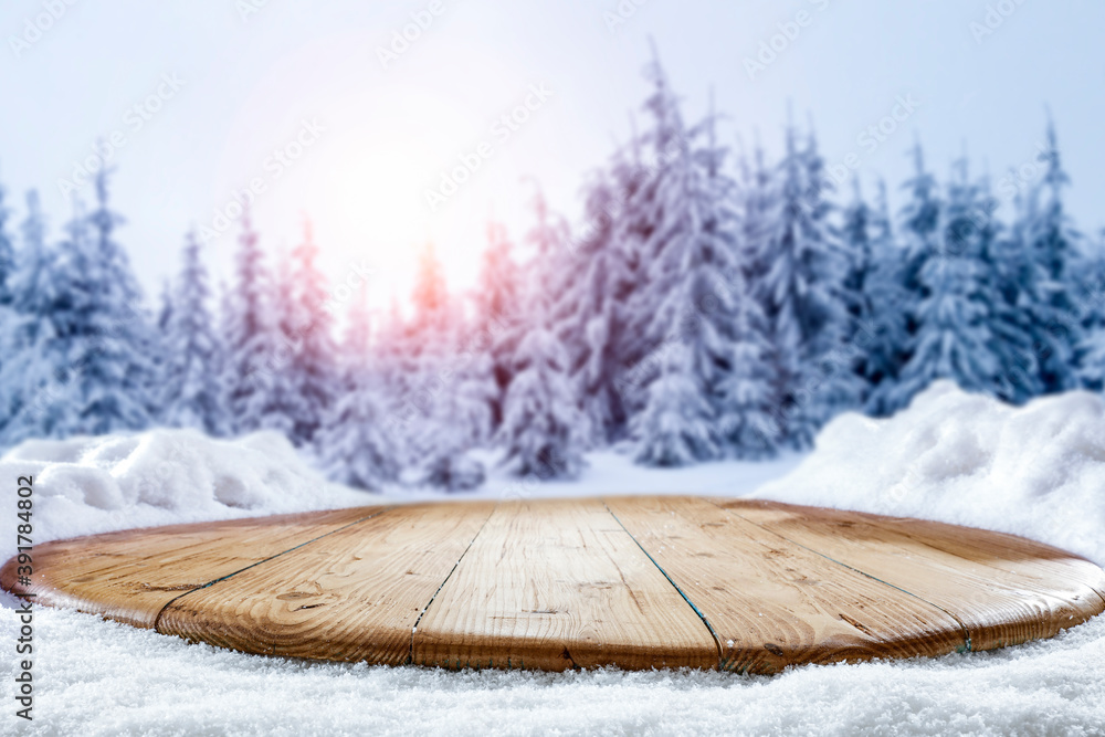 Snow on a wooden table surrounded by a beautiful winter setting sun with a landscape background - obrazy, fototapety, plakaty 