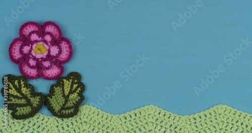 Handmade crochet flower on a blue textile background.