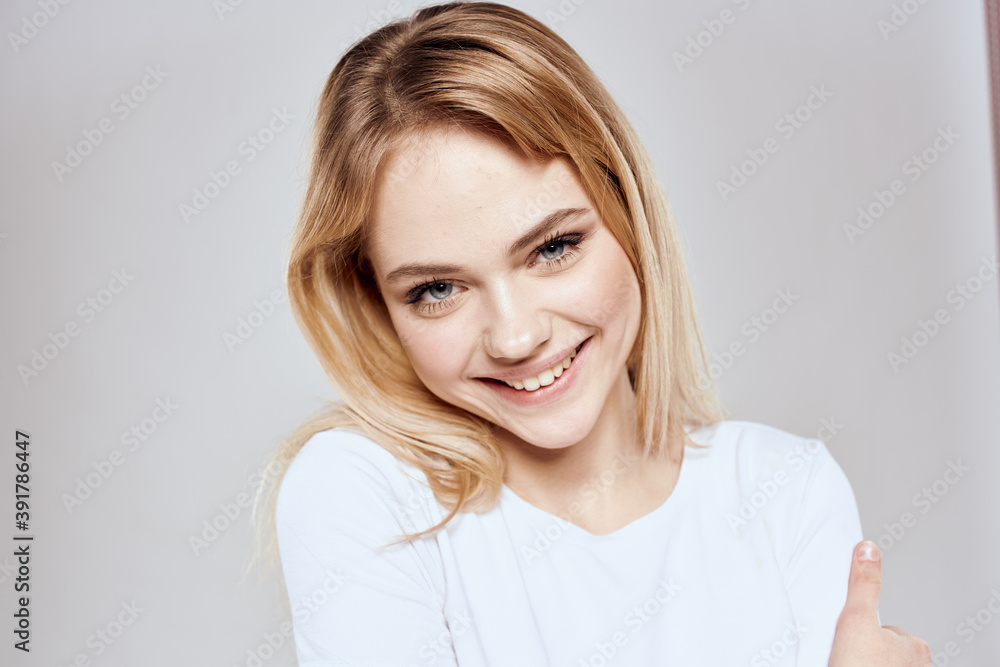 Cheerful blonde woman in white t-shirt cropped view light background Cheerful blonde woman in white t-shirt cropped view light background