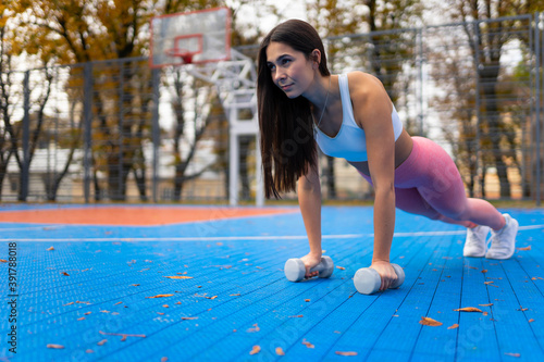 Fitness girl in a plank with dumbbells