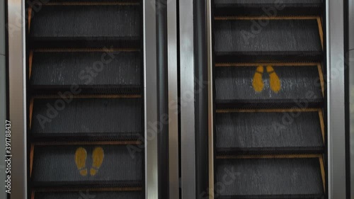 staircase escolator in a shopping center with a footprint sign for keeping a social distance