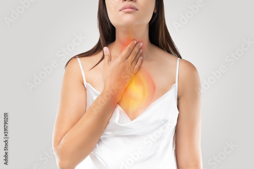 A woman suffering from acid reflux or Heartburn on gray Background
