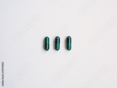 Three green pills, white background. Health concept