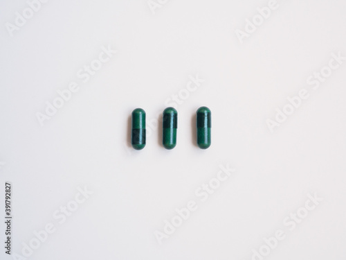 Three green pills, white background. Health concept