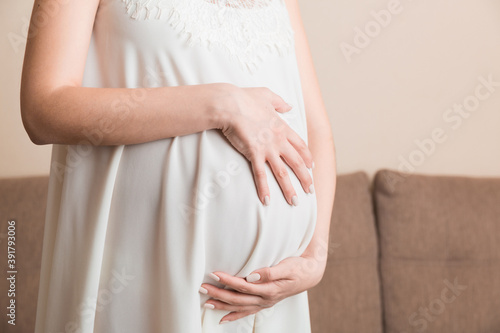 Pregnancy woman in beautiful dress standing on the home