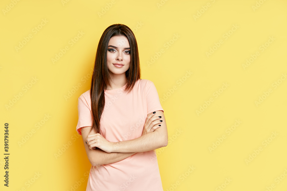 Pretty confident young beautiful woman in casual clothing with crossed arms over yellow background Pretty confident young beautiful woman in casual clothing with crossed arms over yellow background