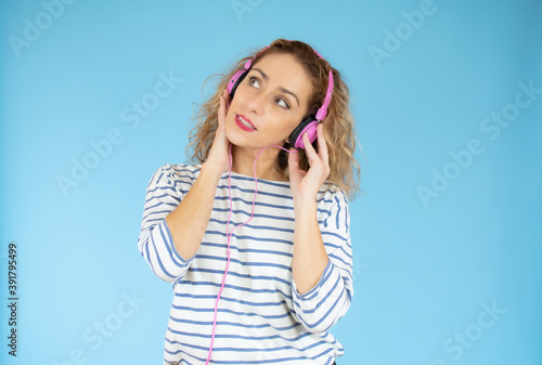 Beautiful woman in headphones listening to music on blue background