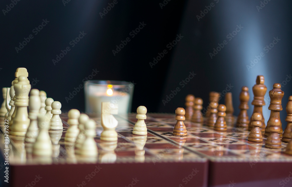 Chess board with figures on a dark background and with candles in the background. Confrontation concept, intellectual long game. Beautiful smart concept. Chess board with figures on a dark background and with candles in the background. Confrontation concept, intellectual long game. Beautiful smart concept.
