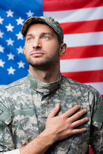 Quadro su tela patriotic military man pledging allegiance near american flag on blurred backgro