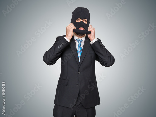 Businessman in suit is wearing balaclava as thief or burglar.