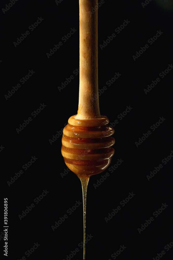 honey dripping from a wooden dipper honey dripping from a wooden dipper