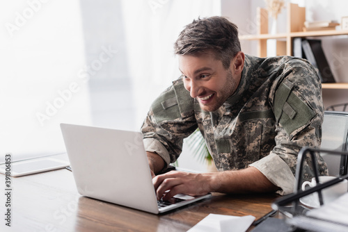 excited military man typing on laptop keyboard