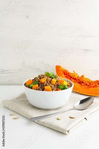 Buckwheat porridge with pumpkin and pasley in a white bowl