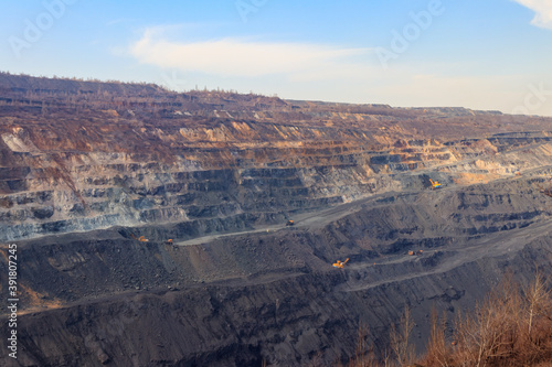 Huge iron ore quarry with working dump trucks and excavators