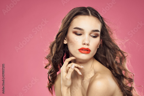 Beautiful woman with red lips on a pink background nude shoulders cropped view