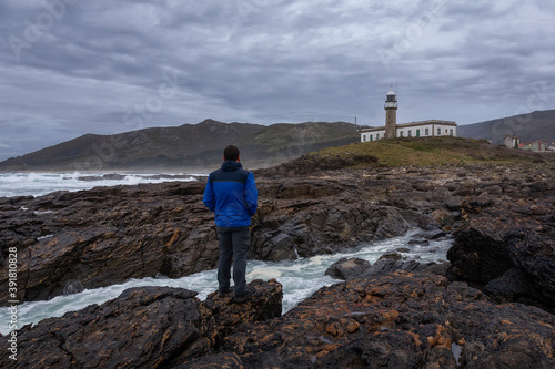 Man looking at a lighthouse in Galicia during a grey winter day