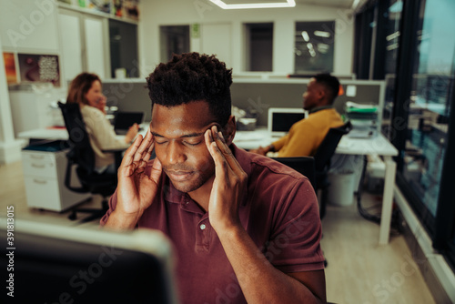 Stressed business man feeling the pressure of deadlines struggling with a headache while trying to complete assignment 