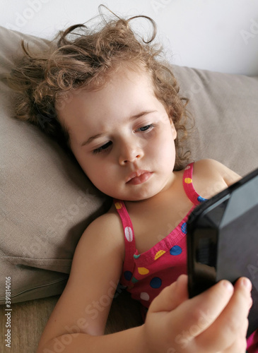 small girl playing with tablet on sofa