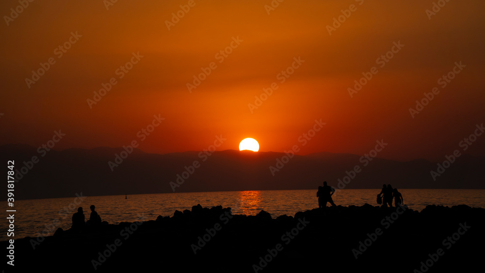 people in silhouette by the sea at sunset