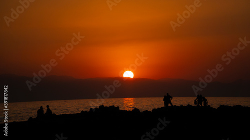 people in silhouette by the sea at sunset